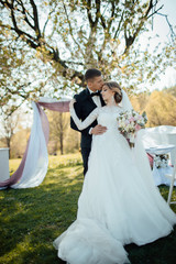 Creative stylish wedding ceremony elegant curly bride and groom outdoors. Marriage photo in white bridal dress posing outdoors