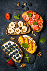 Sweet toast assortment with fresh fruit and berries on black.