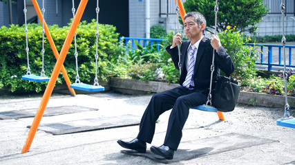 ブランコに乗る中高年男性
