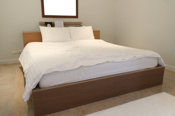 Plain bedroom interior, white pillows and mattress use white linen on wooden bed