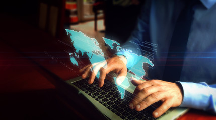 Man typing on keyboard with world map hologram