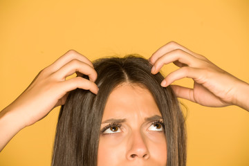 Beautiful young woman with itchy scalp on yellow background - obrazy, fototapety, plakaty