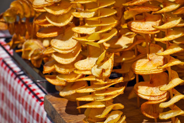 Potato chips on a stick. Natural chips are fried and sold at the fair. Fat street food.