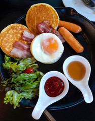 Breakfast - fried egg ,bacon ,sausages and pancakes with sauce.