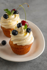 cupcakes with cream, blueberries and mint on a grey background. Copy space.