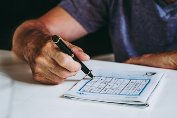 Mains d'un homme en train de faire un jeu de sudoku