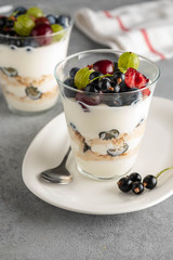 Tiramisu with berries in glasses on grey background. Italian dessert. Copy space.