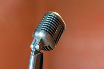 Fototapeta na wymiar Retro vintage metal stainless steel microphone on stage isolated on orange background.