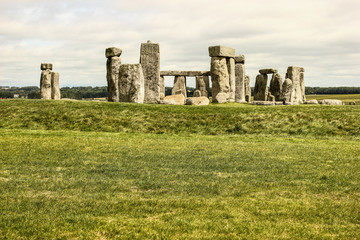 Stonehenge on a cloudy and windy day. Green grass in the foreground, clouds in the background....