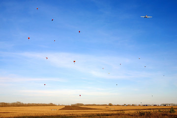 Mass parachute descent in a flying school in autumn in a blue sky.