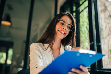 Portrait of a young woman filling questionnaire, low angle view.