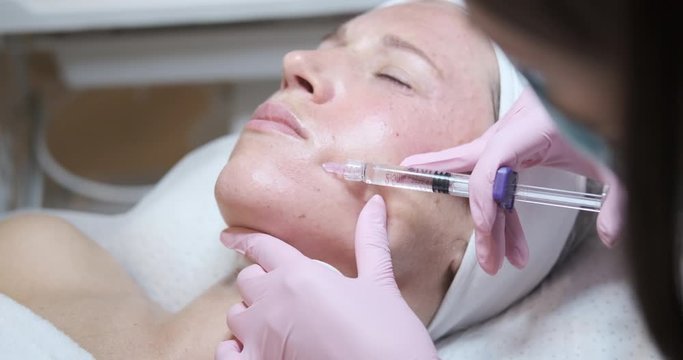 Woman receiving cosmetic injection of botox in her cheek
