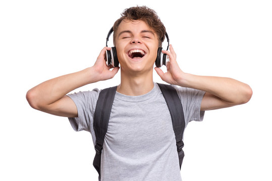 Happy teen boy with headphones and backpack, isolated on white background. Cheerful child listening to music and singing song. Emotional portrait of handsome teenager enjoying music Back to school.