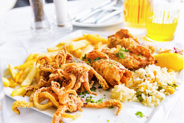 Fried squids, french fries and rice. Seafood plate served in restaurant.