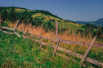 Fototapeta na wymiar Colorful mountain countryside landscape with a wooden fence
