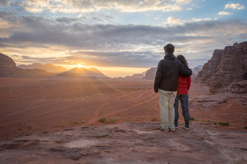 A couple enjoying sunrise over landscape and mountains in Wadi Rum in Jordan