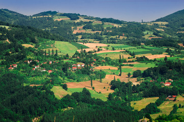 Landscape view of mountain farmland with village houses and tall cypress trees