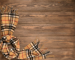Woolen scarf with a pattern on a wooden brown background. Autumn concept. Place for text design. Flat layout top view.