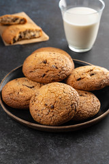 Chocolate chip cookies with milk on black table. Copy space.