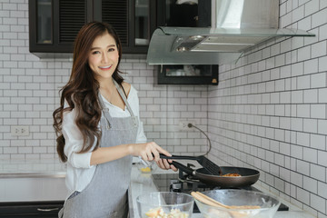  Beautiful Asian girl cooking in a white kitchen