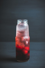 Cherry drink with berries and ice in small bottle. Selective focus. Shallow depth of field.