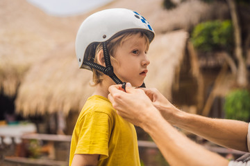 Trainer helps the boy to wear helmet before training skate board