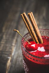 Cherry smoothie with cinnamon in old fashioned glass on the rustic wooden background. Selective focus. Shallow depth of field.