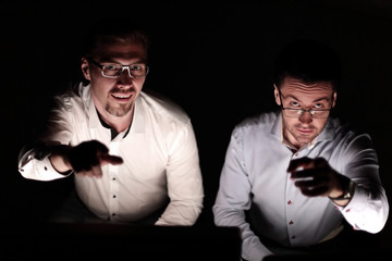 close up.two colleagues sitting at their Desk and pointing at you