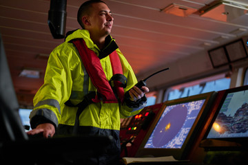 Navigator. pilot, captain as pat of ship crew performing daily duties with VHF radio, binoculars on...