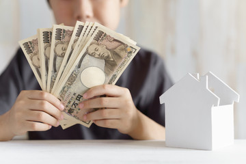 1万円札を持つ小学生の男の子と家のオブジェ