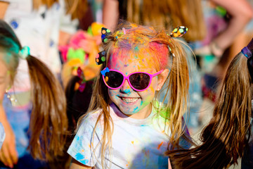 The portrait laughs the girl in the sunglasses at Holi paint party