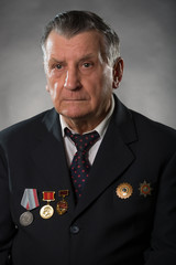 Portrait of an elderly gray haired man. On his chest medals of the Soviet period. A war veteran and hero of socialist labor. Studio photography.