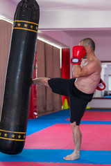 Muay thai fighter hitting the heavy bag in the gym