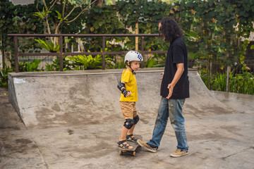 Athletic boy learns to skateboard with a trainer in a skate park. Children education, sports