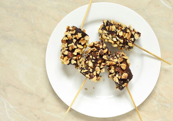 Frozen banana in chocolate and hazelnuts, top view, copy space
