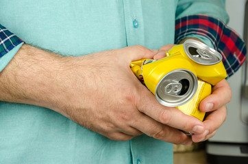 Man's hands holding two empty crumpled beer cans