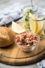 Norddeutsche Friesische Nordseekrabben in Glas Schale mit Brötchen, Gurkensalat und Zitronen auf Holz Brett