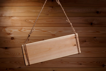 Wooden signboard on a rough rope on a beautiful wooden background