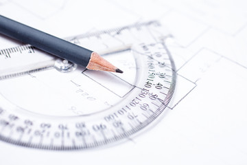 Pencil on a transparent protractor against the background of drawing details