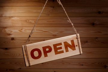 Wooden signboard with the words OPEN on a rough rope on a beautiful wooden background