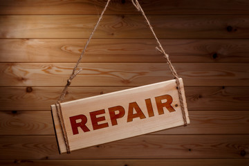 Wooden signboard with the words REPAIR on a rough rope on a beautiful wooden background