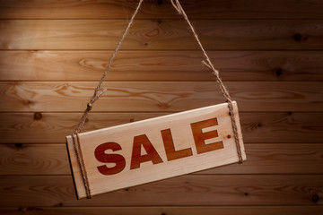 Wooden signboard with the words SALE on a rough rope on a beautiful wooden background