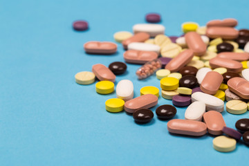 many scattered Colorful medical pills on pastel blue background