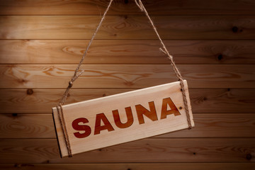 Wooden signboard with the words SAUNA on a rough rope on a beautiful wooden background