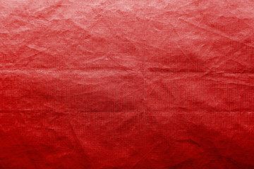 Dirty crumpled red synthetic fabric texture with a well-traced light and shadow pattern