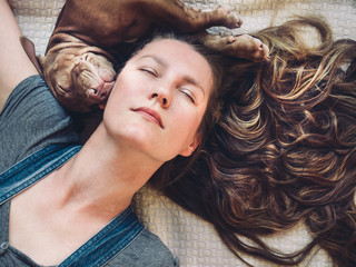 Beautiful woman and young, charming puppy, resting on a plaid. Close-up, white isolated background. Studio photo. Concept of care, education, training and raising of animals