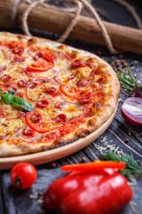 Aromatic pizza with hunting sausages, onions and tomatoes near with vegetables
