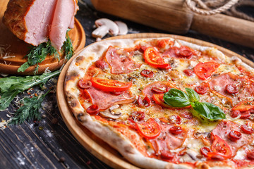 Aromatic pizza with sausage and tomatoes is decorated with basil