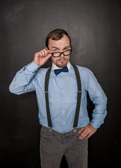 Handsome strict teacher in eyeglasses looking at you on blackboard