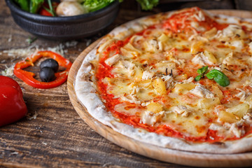 Delicious pizza with chicken and pineapple decorated with basil